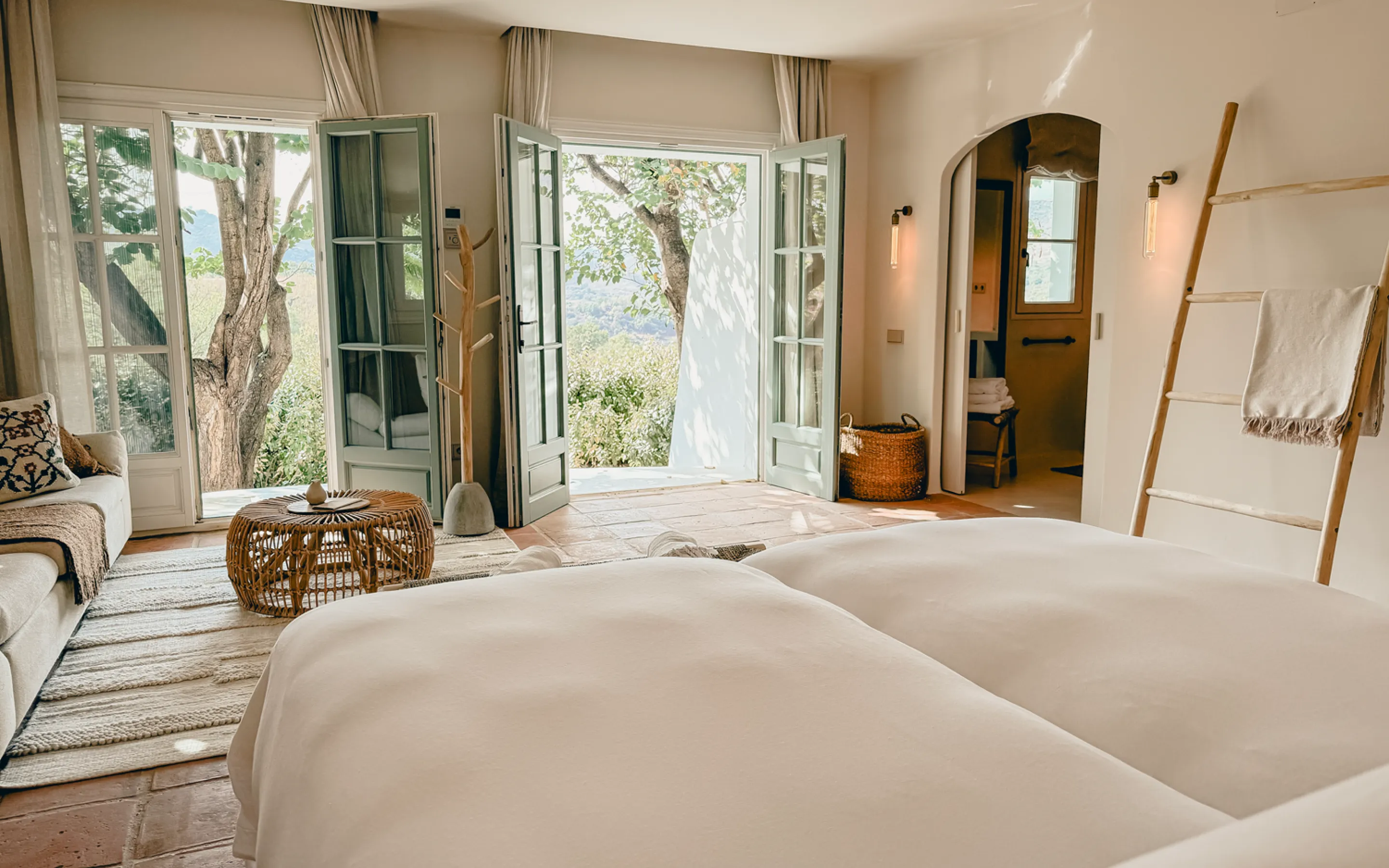 A quiet bedroom at Viluz, doors opening to the hills